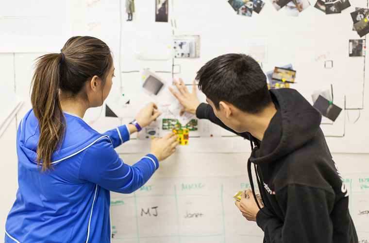 two individuals working at board on wall