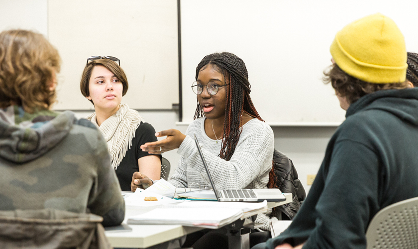 a group of combined degree student gather around a table