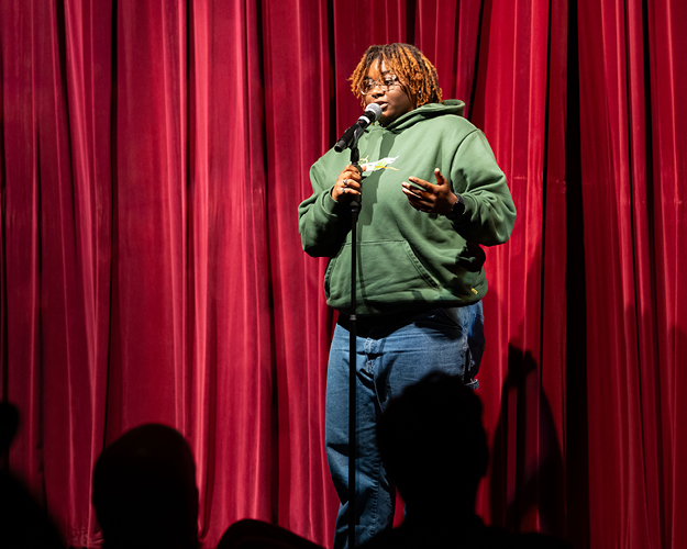 A comedy writing and performance degree student performs on stage