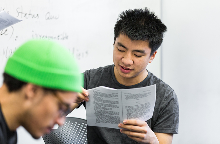 A student reads off a page to another in a cultural studies class.