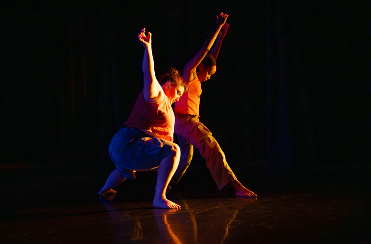 Dancers performing lit brightly on a dark stage