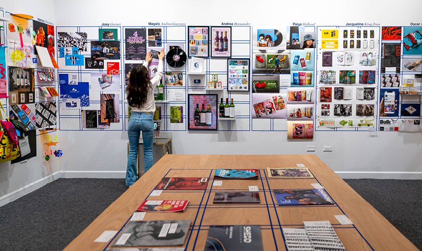 a design management degree student hangs artwork on a gallery wall