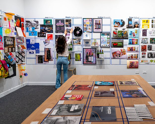 a design management degree student hangs artwork on a gallery wall