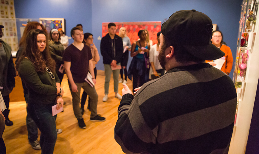 a large group of entrepreneurship and innovation students listen to a presenter on a field trip