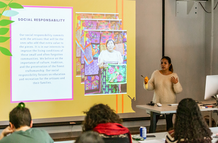 A student presents to classmates at the front of the room