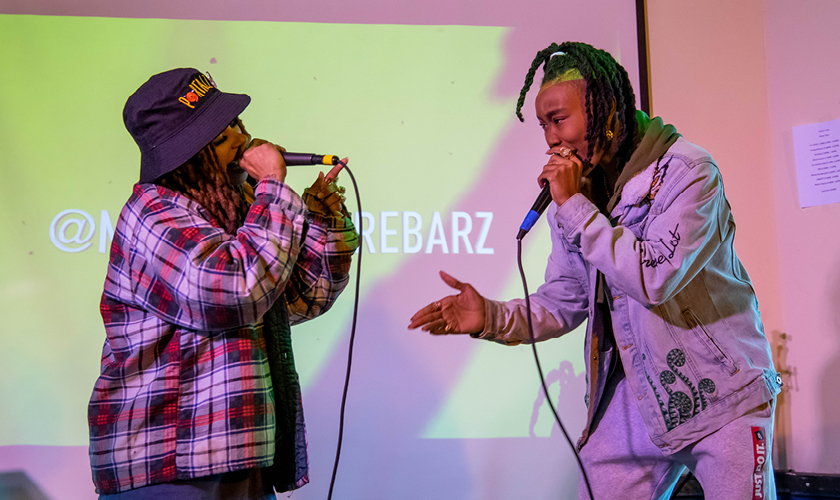 two masters in entrepreneurship for creatives rap into microphones on stage