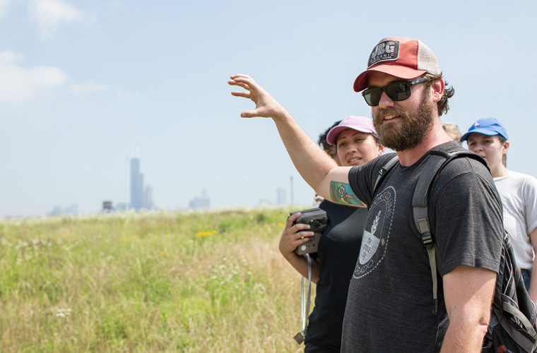 A faculty member for environmental studies degree talks to students on a trip to a field