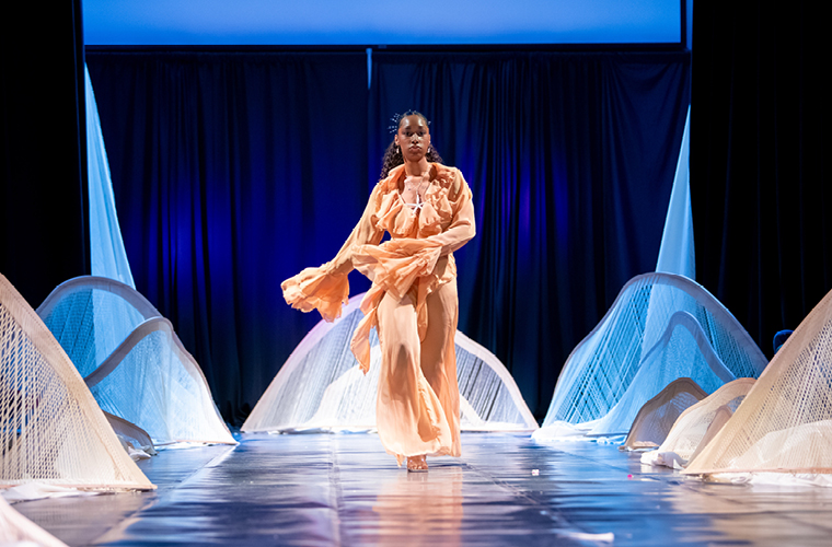 a fashion design student model walks down the runway at a fashion show