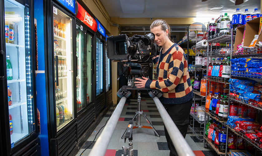 a film student stands behind a large camera on the set of a student film