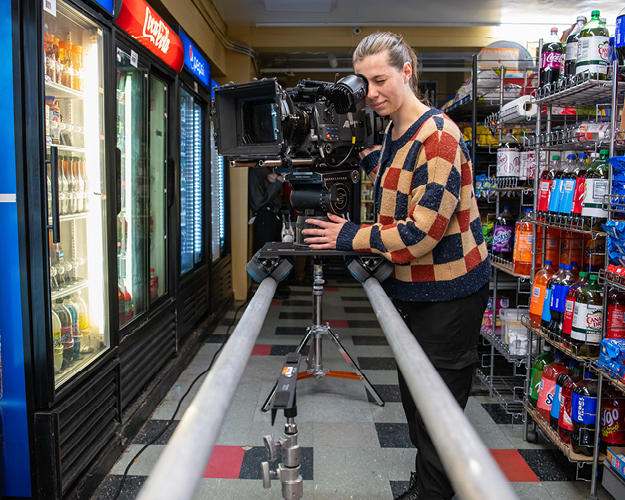 a film student stands behind a large camera on the set of a student film