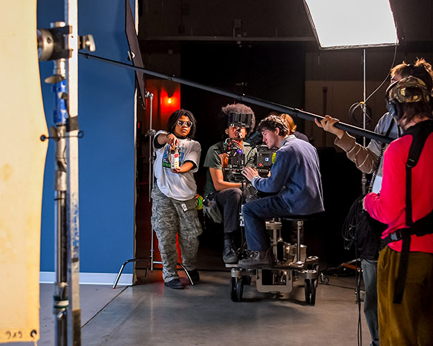 crew of students on film set with several behind moving camera