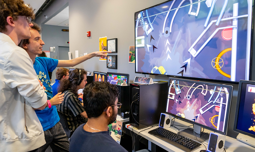 students gather around monitors to play student designed games 