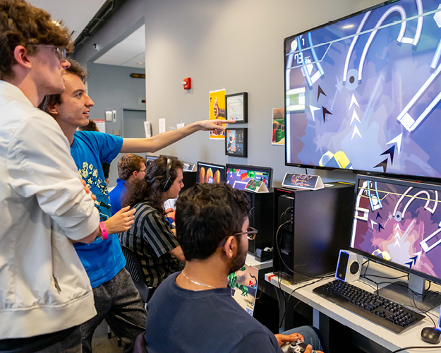 students gather around monitors to play student designed games 