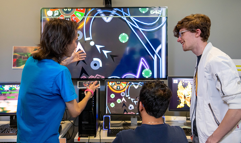 game design students gather around monitors to play student made games