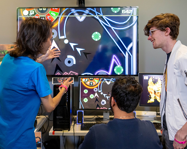 game design students gather around monitors to play student made games