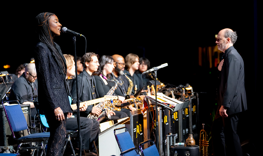 photo of composer in front of orchestra with movie screen behind them