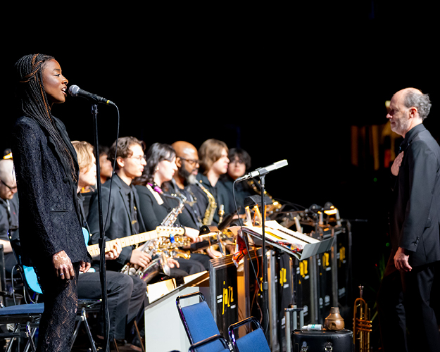 photo of composer in front of orchestra with movie screen behind them