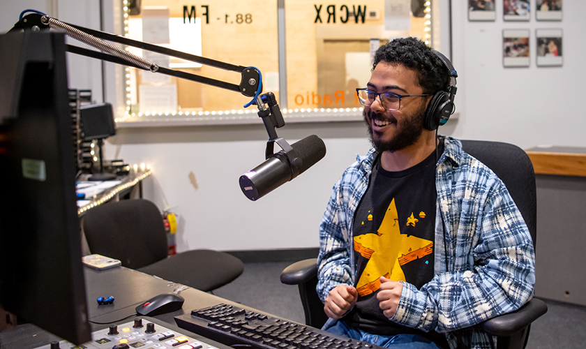 a radio broadcasting major student speaks on air in a college radio station booth