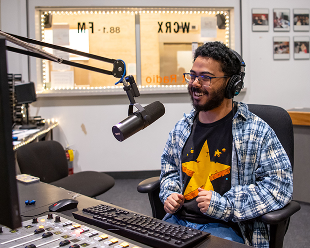 a radio broadcasting major student speaks on air in a college radio station booth