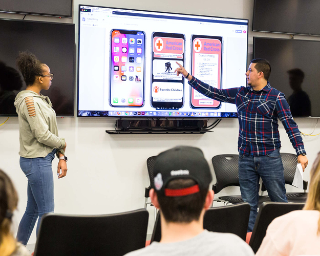 two social media students present in front of a class for a social media course