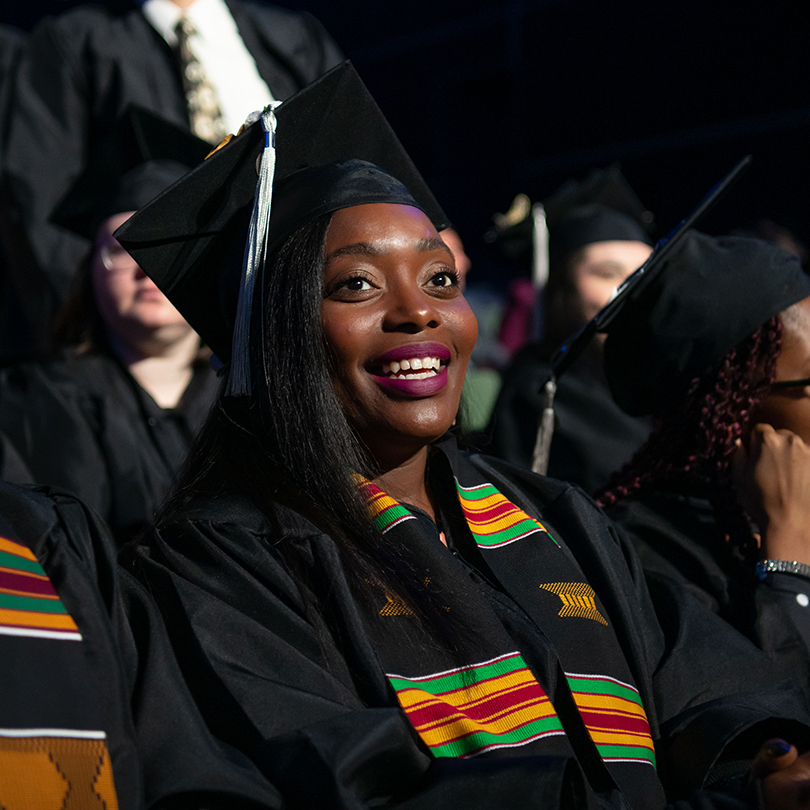 smiling student wearing cap and gown at commencement ceremony