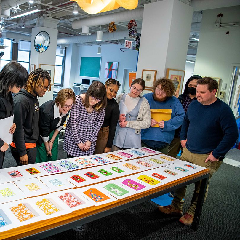 students gathered around large desk looking at print samples