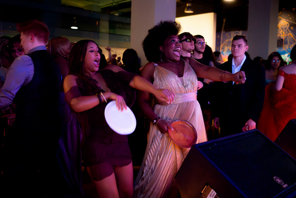 Two Columbia students dance and smile at the front of a crowded room.