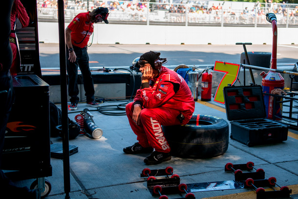 A NASCAR crew member sits on a tire in the pit lane during downtime at the NASCAR Chicago Street Race.