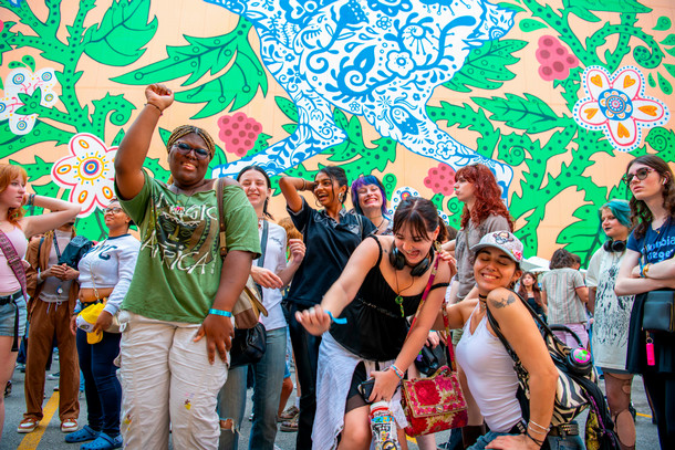 students dance at new student convocation in front of a colorful mural