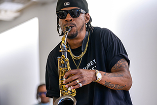 person wearing sunglasses and hat playing saxophone