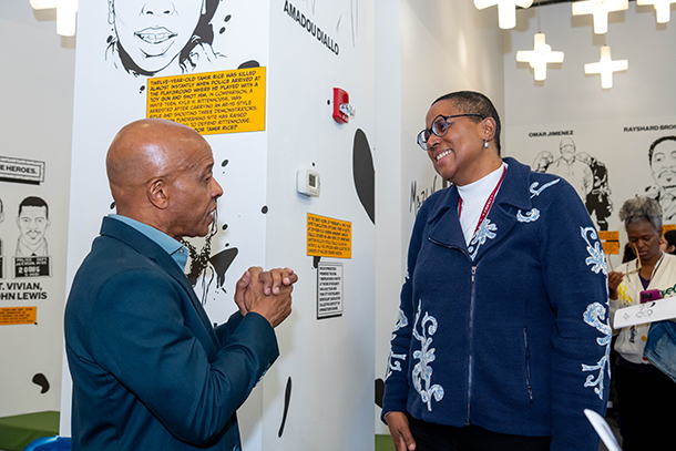 two people talking with art on walls in background