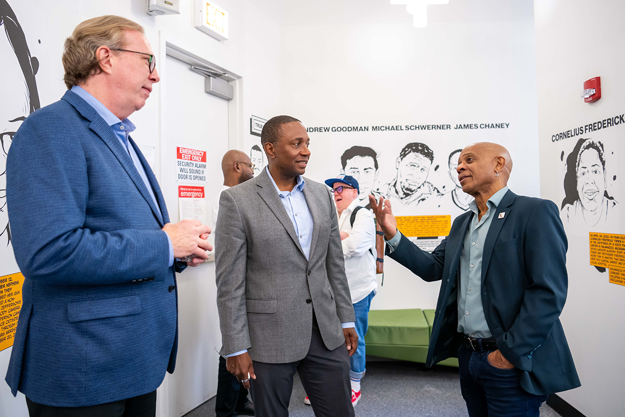 three people having conversation with artwork on walls in background