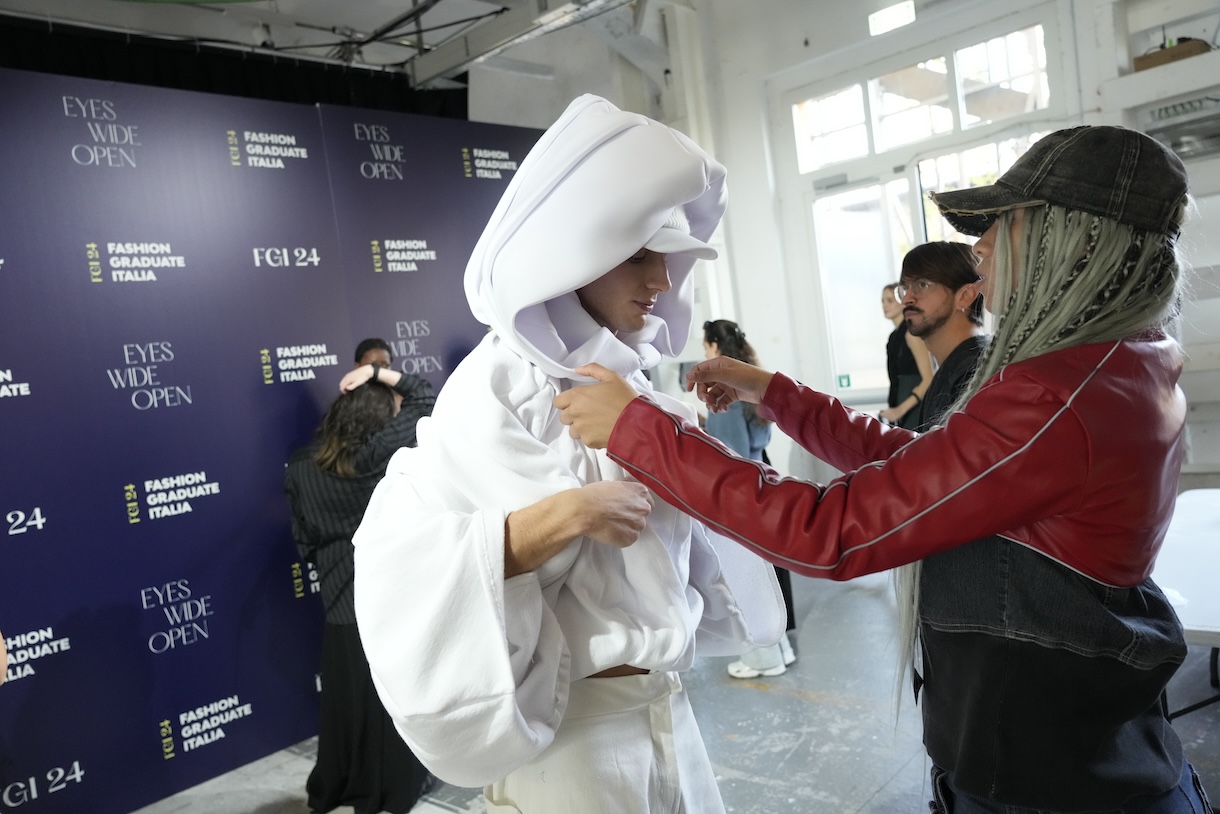 Student designer Joelle Helena Olabode (BFA Fashion Design ’25) adjusts the hood of one of her designs on a model backstage at the City to City fashion show in Milan, Italy. Photo by Daniele Schiavello