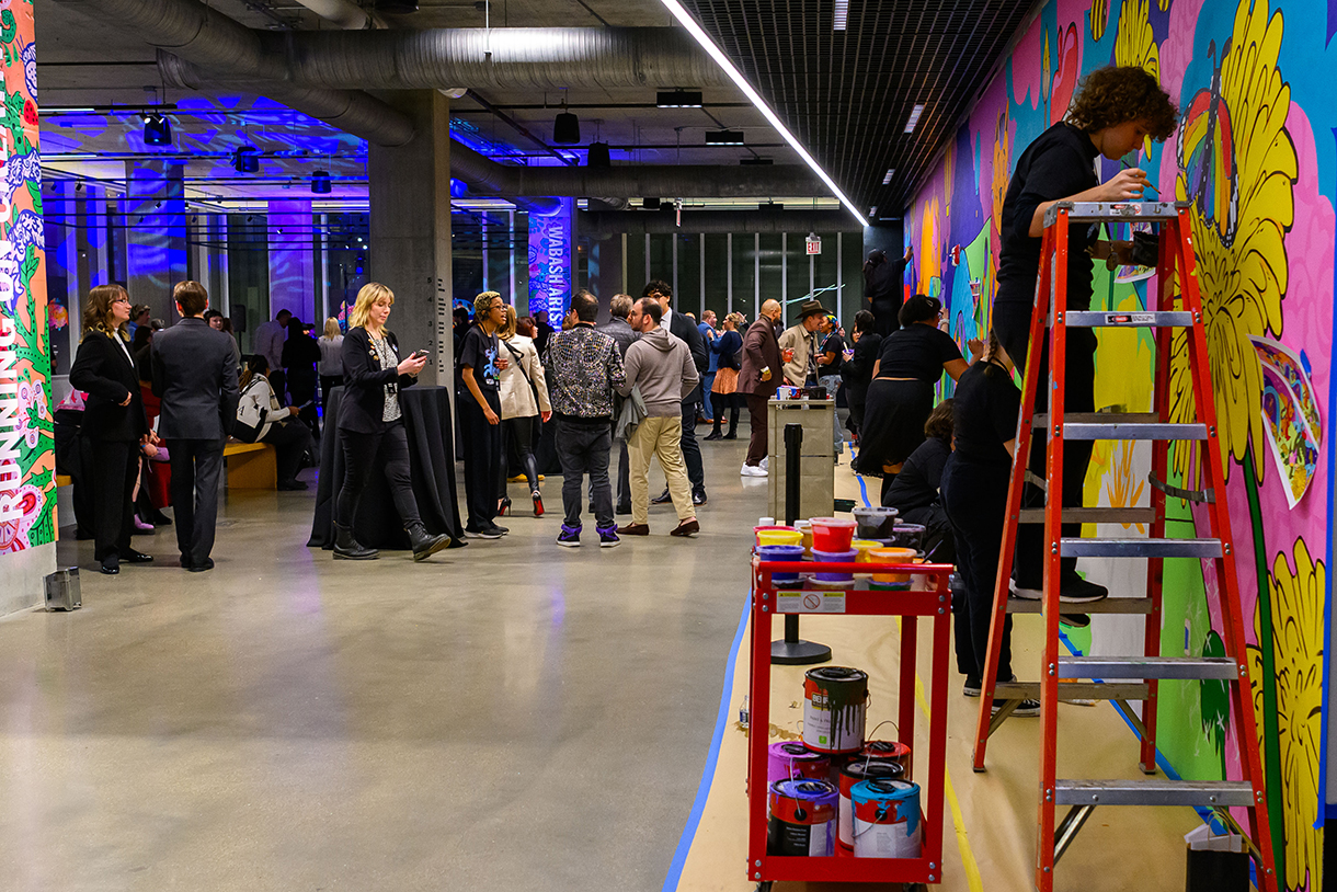 a mural is painted as attendees peruse the activation and exhibit space